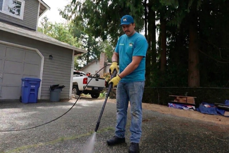 3 Amigos crew member pressure washing a driveway